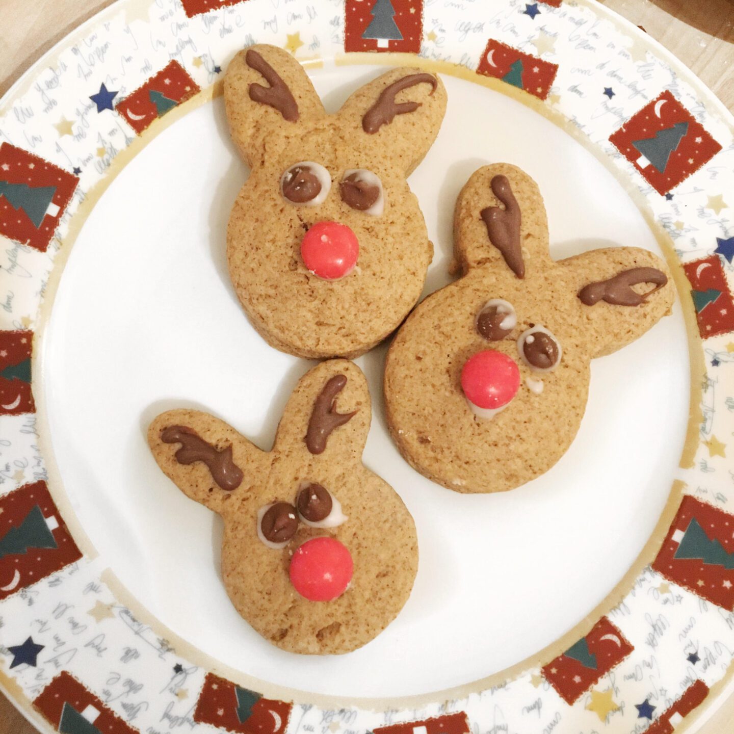 Three reindeer cookies on a Christmas plate