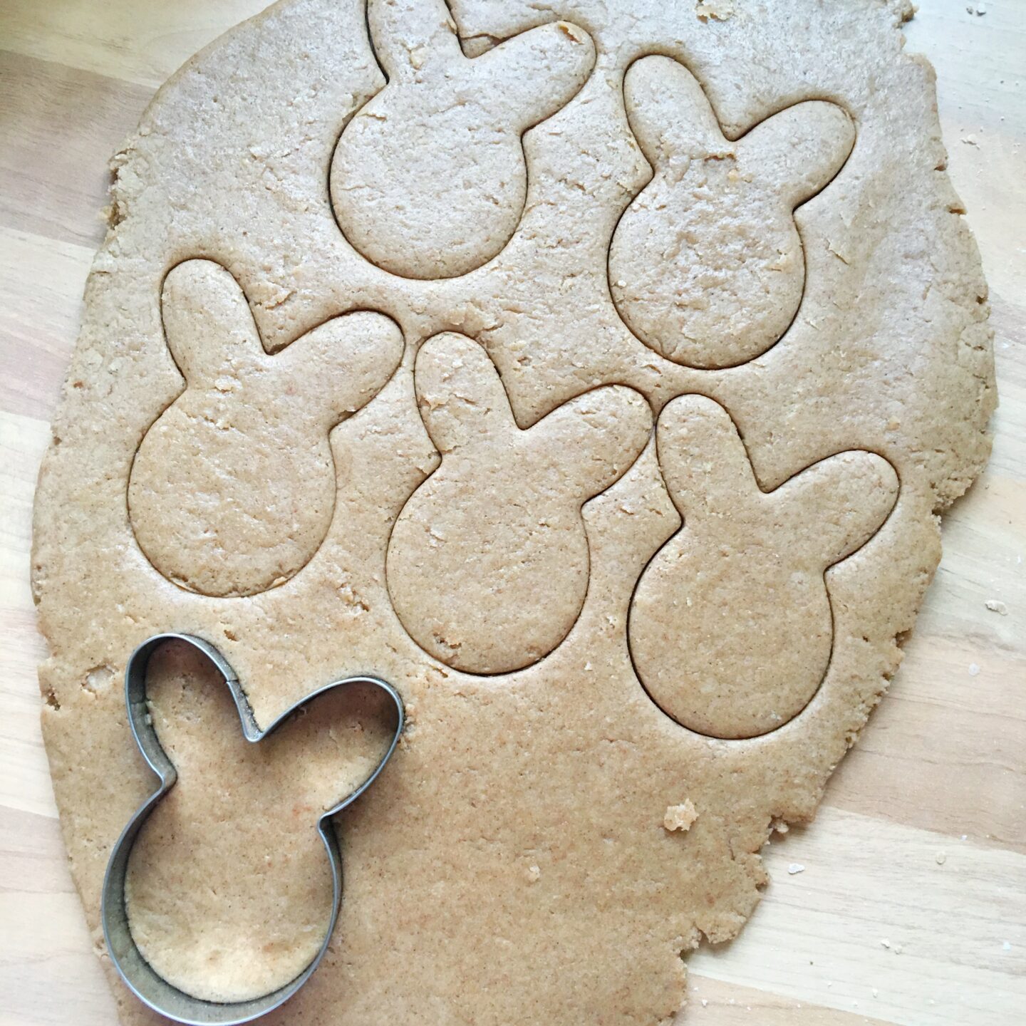 The dough rolled out, with cookie imprints and the cookie cutter at the bottom