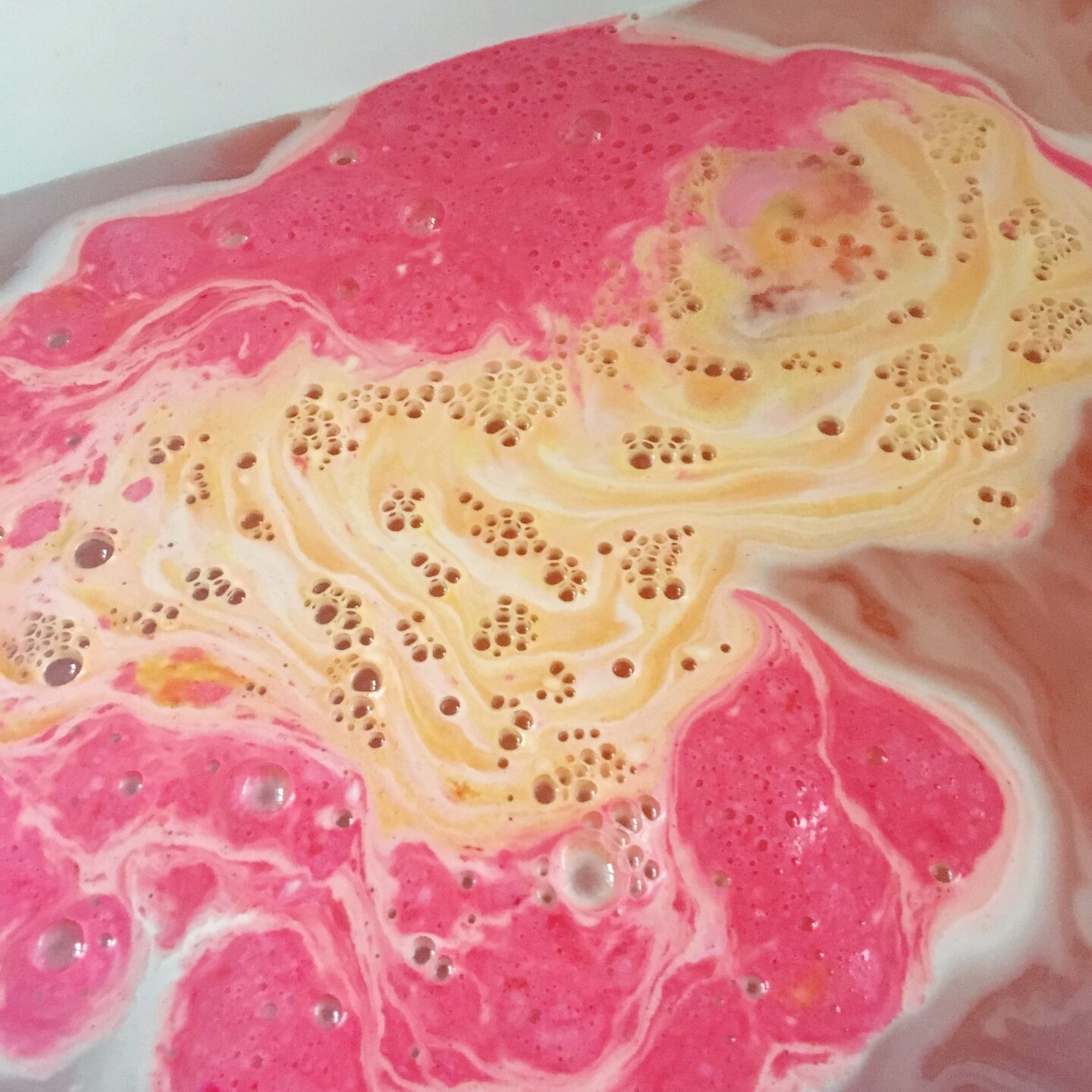 Lush christmas sweater bath bomb in water showing how the orange has dispersed.