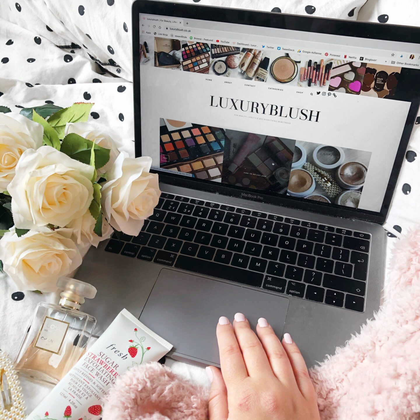 Laptop open to the homepage of my blog. White roses to the side, with perfume, a face scrub and a pearl hair clip | Five Reasons Why I Love Blogging
