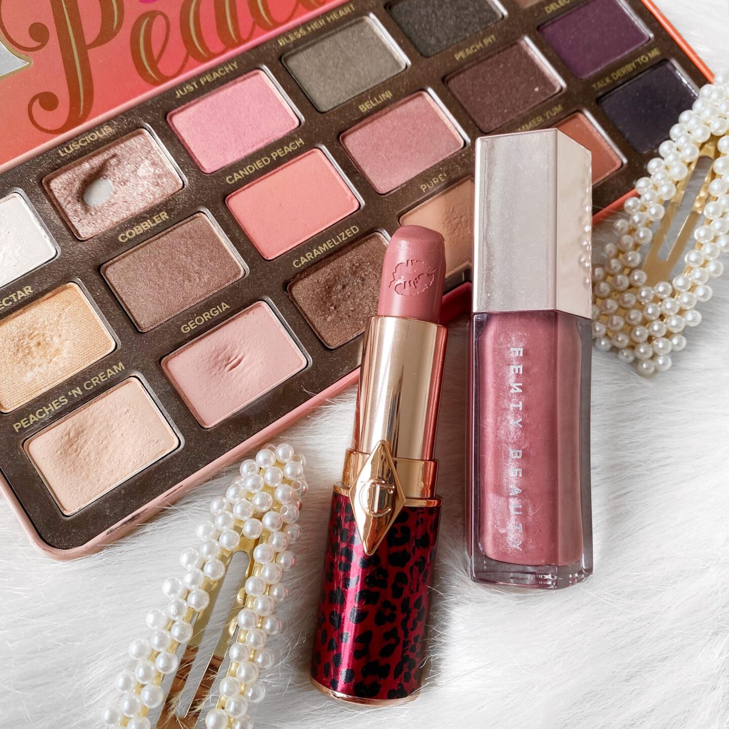 makeup flatlay of peach eyeshadow palette, pink lip products