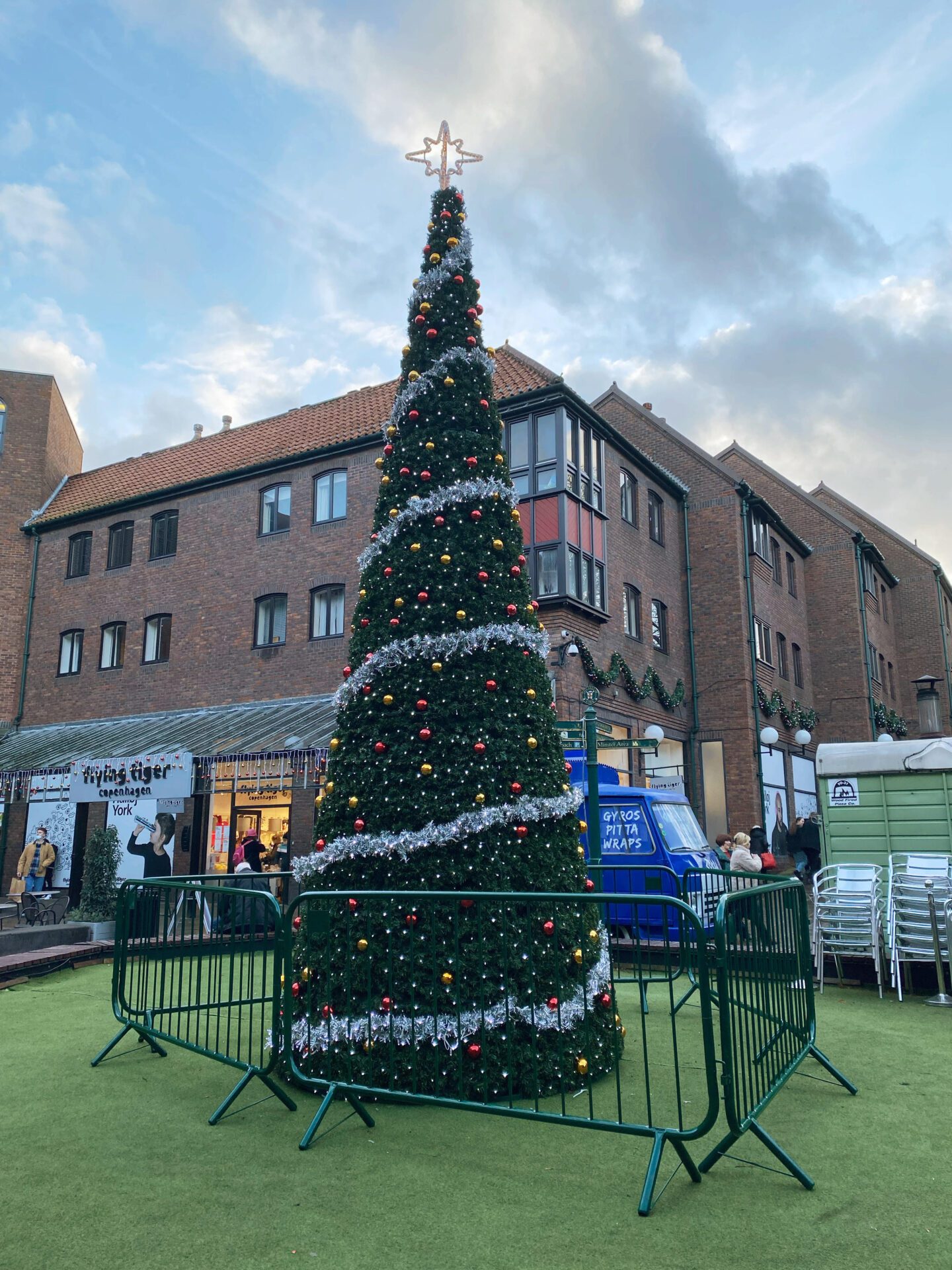 Christmas tree with silver tinsel, and red and yellow baubles in the middle of a York street